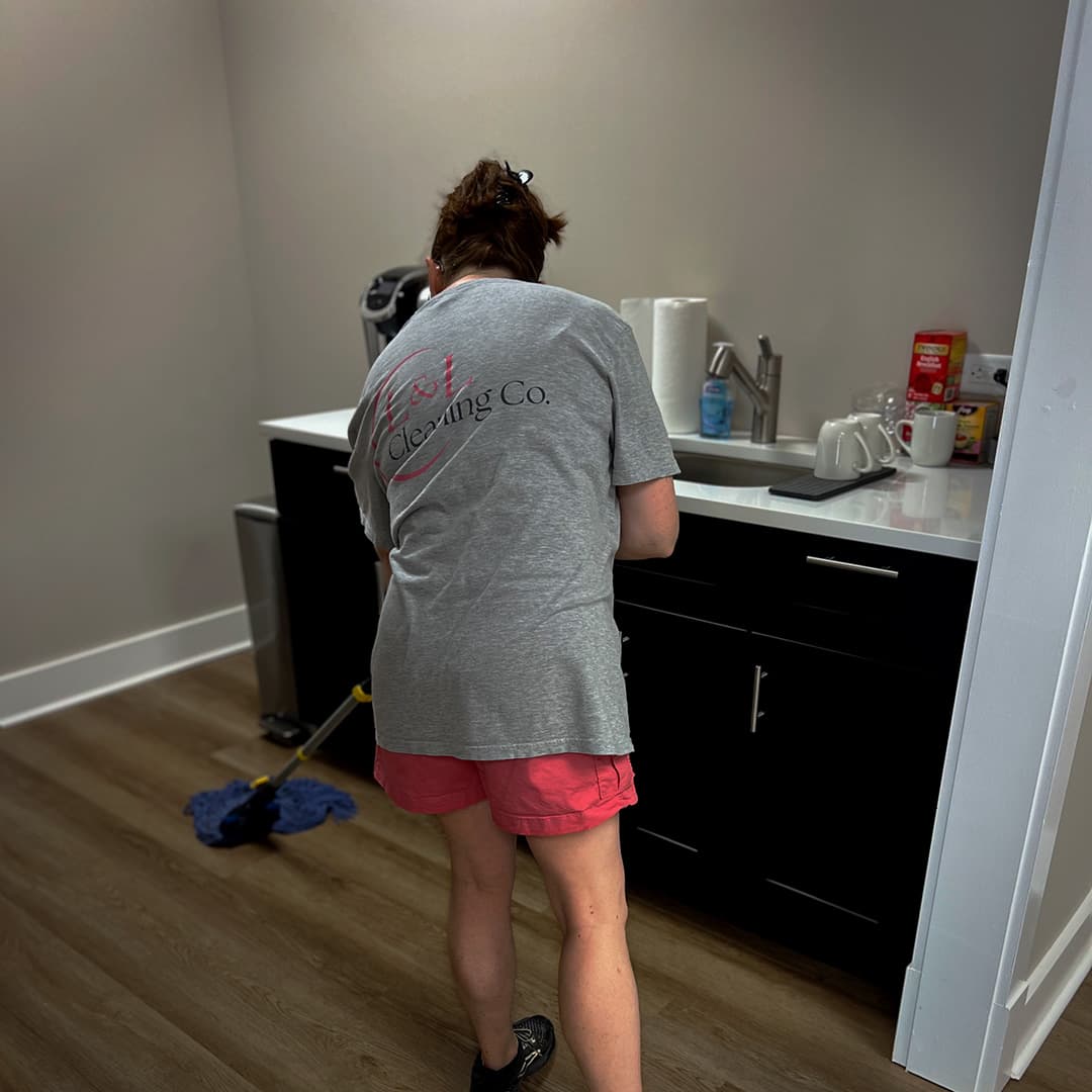 A woman mopping a pristine breakroom floor.