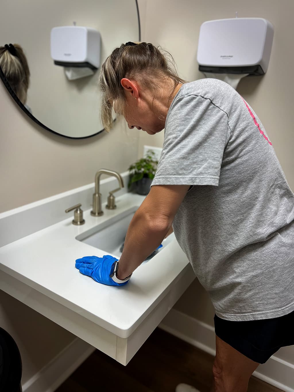A woman cleaning a bathroom sink.